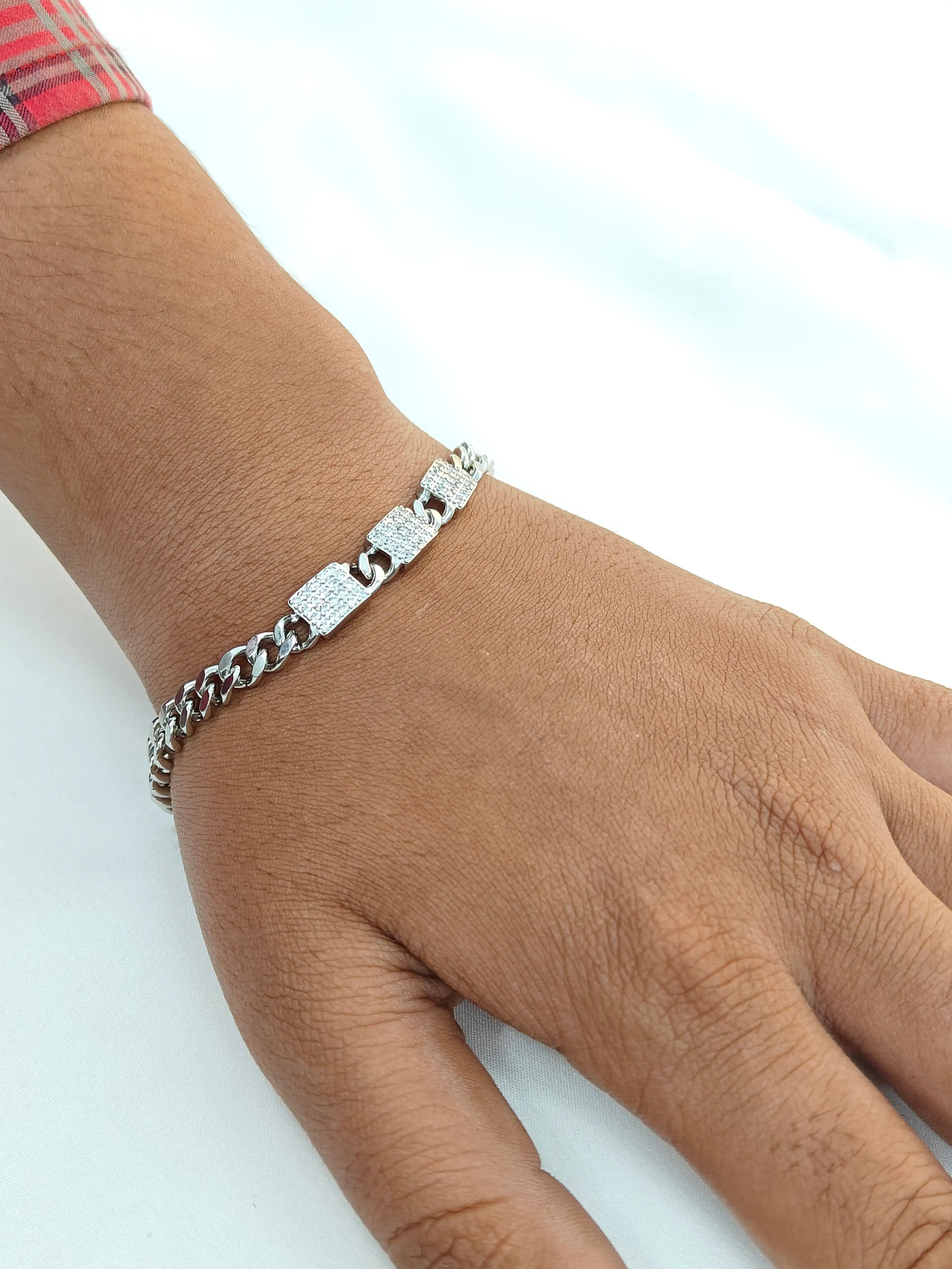 Silver bracelet on a wrist against a light background